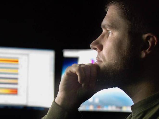 Man is looking at graphs on computer monitors